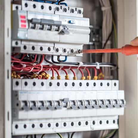 Man, an electrical technician working in a switchboard with fuses. Installation and connection of electrical equipment. Close up.